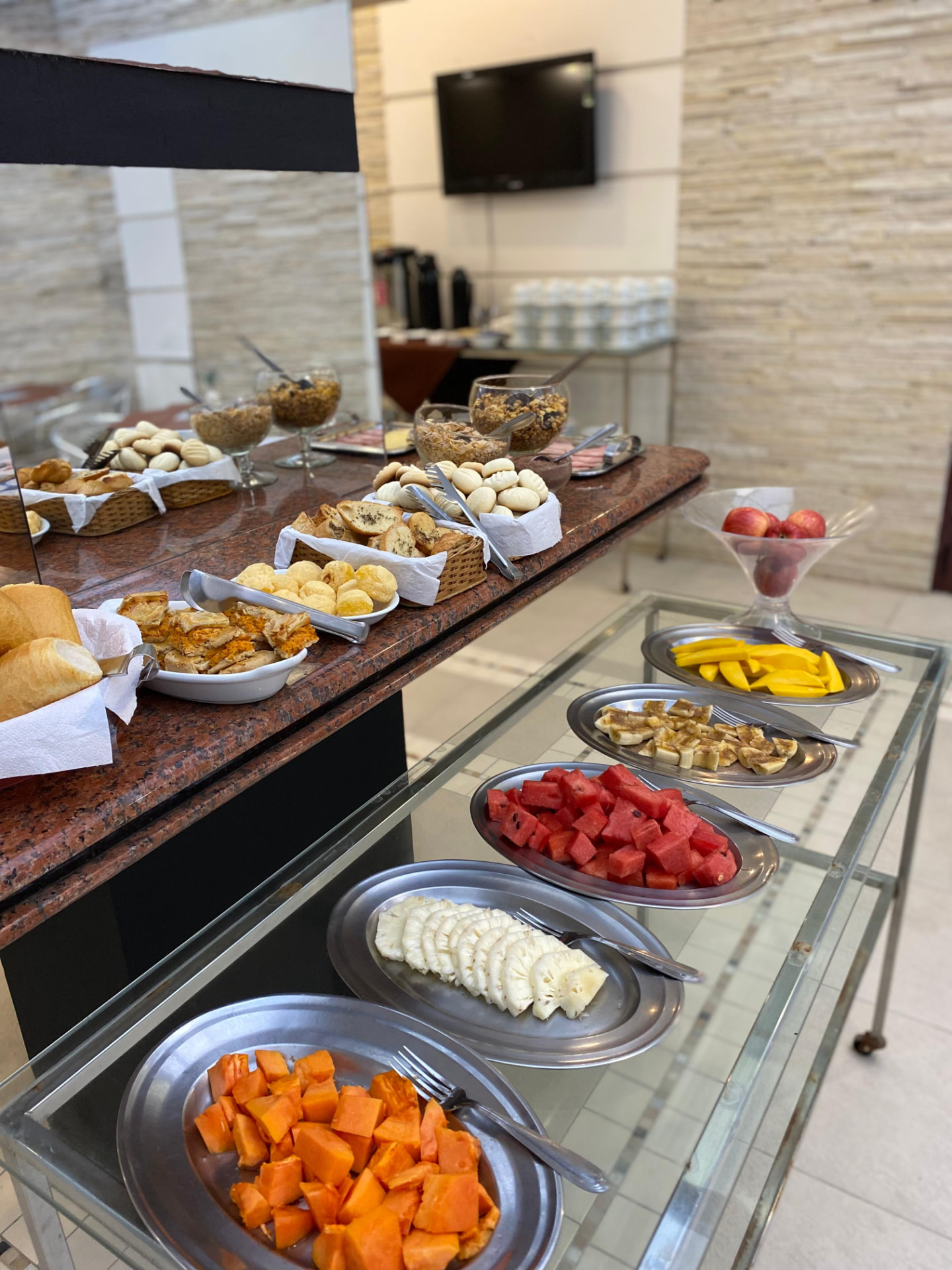Mesa de café da manhã com pães, frios, cereais e frutas frescas